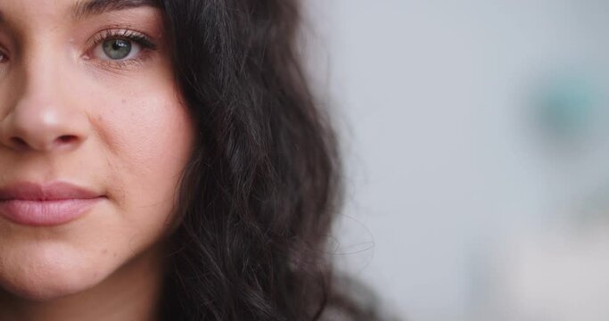 Close-up of half woman face with perfcet skin and light nude make-up. Fascinating female grey eyes with shiny green shadow.