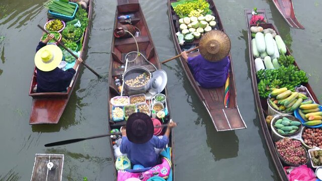 Different kinds of foods, fruits and vegetables sold on boats in the canal at floating market Samut Songkhram, Thailand.