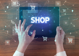 Close-up of a hand holding tablet with SHOP inscription, online shopping concept