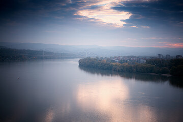 Beautiful autumn landscape, Danube river on a foggy cloudy day, clouds and sky are reflected in water