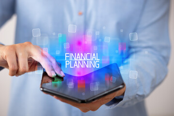 Young man holding a foldable smartphone with FINANCIAL PLANNING inscription, educational concept