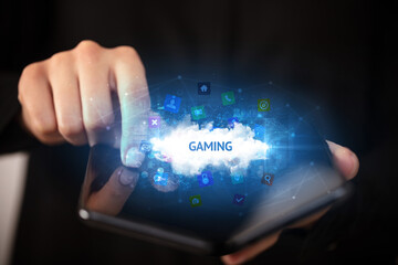 Businessman holding a foldable smartphone with GAMING inscription, technology concept