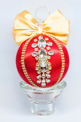 Red Christmas ball in rhinestones for Christmas tree decoration. Christmas toy. Christmas toy for decorating a Christmas tree on a white background. Shining crystals on a red ball.