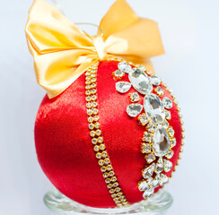 Red Christmas ball in rhinestones for Christmas tree decoration. Christmas toy. Christmas toy for decorating a Christmas tree on a white background. Shining crystals on a red ball.