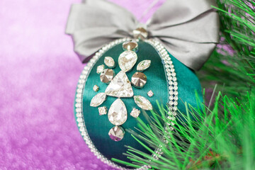 Green Christmas ball in rhinestones for decorating the Christmas tree. Christmas toy. Christmas toy for decorating a Christmas tree on a lilac background. Shining crystals on a green ball.