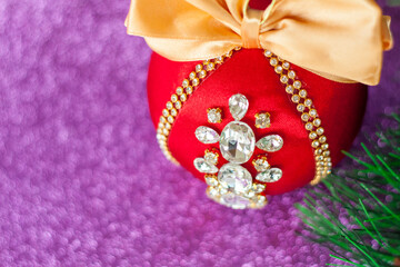 Red Christmas ball in rhinestones for Christmas tree decoration. Christmas toy. Christmas toy for decorating a Christmas tree on a lilac background. Shining crystals on a red ball.