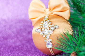 Golden Christmas ball in rhinestones for decorating the Christmas tree. Christmas toy. Christmas toy for decorating a Christmas tree on a lilac background. Shining crystals on a Golden ball.