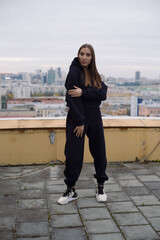 Obraz premium Full height photo of young woman, standing on roof of tall building in large city.