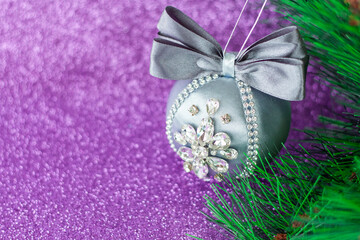 Grey Christmas ball in rhinestones for Christmas tree decoration. Christmas toy. Christmas toy for decorating a Christmas tree on a lilac background. Shining crystals on a gray ball.