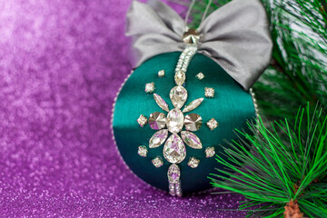 Green Christmas ball in rhinestones for decorating the Christmas tree. Christmas toy. Christmas toy for decorating a Christmas tree on a lilac background. Shining crystals on a green ball.