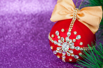 Red Christmas ball in rhinestones for Christmas tree decoration. Christmas toy. Christmas toy for decorating a Christmas tree on a lilac background. Shining crystals on a red ball.