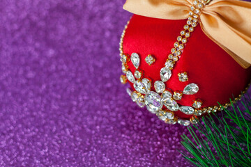 Red Christmas ball in rhinestones for Christmas tree decoration. Christmas toy. Christmas toy for decorating a Christmas tree on a lilac background. Shining crystals on a red ball.