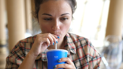 Young woman enjoying a drink with the straw. Drinking cola or soda pop with a straw. Close up...