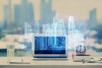 Desktop computer background in office and big town buildings hologram drawing. Double exposure. Smart city concept.