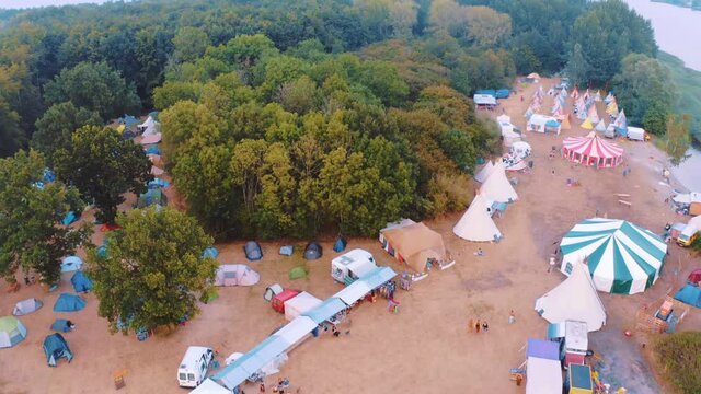 Carnival And Campsite Near A Vast Forest  At The Edge Of  A Lake - aerial shot