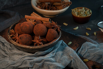 Craft chocolate truffles on plate with cocoa powder and anise, cinnamon, cardamom.