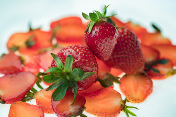 ripe Strawberry slices with green fresh leaves on a white background close up