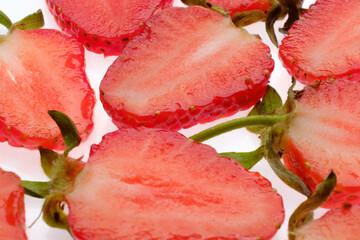 ripe Strawberry slices with green fresh leaves on a white background close up