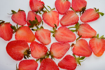 ripe Strawberry slices with green fresh leaves on a white background close up