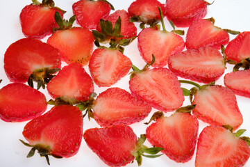 ripe Strawberry slices with green fresh leaves on a white background close up