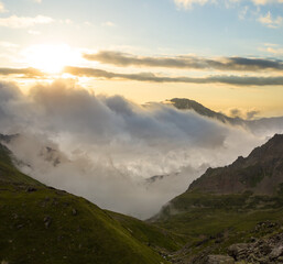 mountain valley in a mist and dense clouds at the sunset