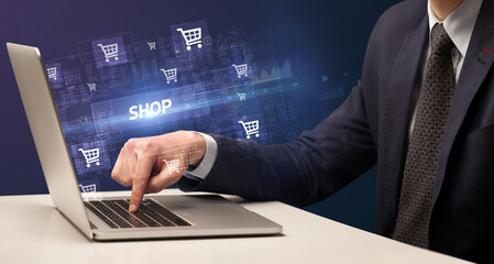 Businessman working on laptop with SHOP inscription, online shopping concept