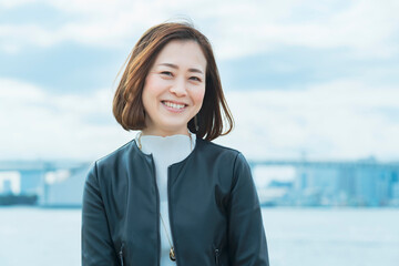 屋外で笑顔を見せるオフィスカジュアルスタイルの女性