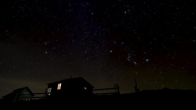 Timelapse of moving stars in night sky above the houses. 4K