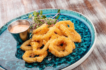 Squid rings fried in batter with sauce on a decorative plate