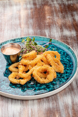 Squid rings fried in batter with sauce on a decorative plate