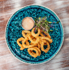 Squid rings fried in batter with sauce on a decorative plate
