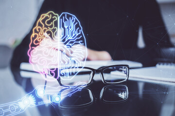 Double exposure of writing hand on background with brain hologram. Concept of learning.
