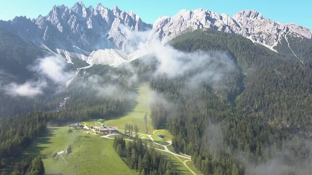 Aerial of a Ski Slope during Summer, high mountain peaks with cloud mist, Innichen South Tirol