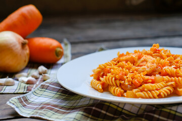 Thai Italian fusion food Stir fried macaroni with ketchup and carrot and shrimps served in white plate on wooden table,delicious European Food Traditional Style decorate