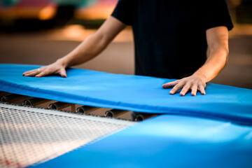 view on young man's hands that lie on blue surface of the trampoline