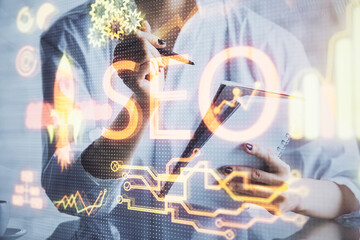Multi exposure of woman's hands making notes with SEO icon. Concept of Search engine optimization