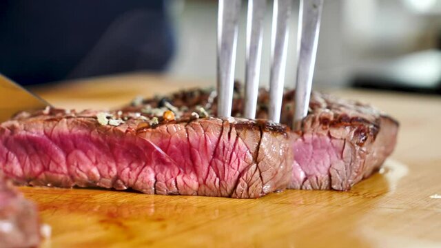 man cut beef steak on woodenboard