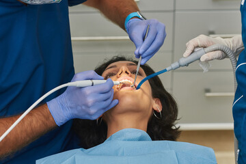A woman lying in a dental office chair cleans her teeth.