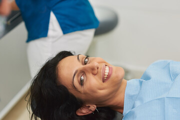 Beautiful patient smiling lying on the chair in the dental office.