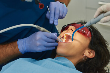 A woman lying in a dental office chair cleans her teeth.