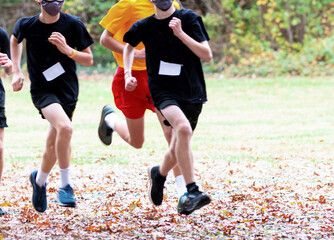 Boys running in a high school cross country race wearing face masks during COVID-19