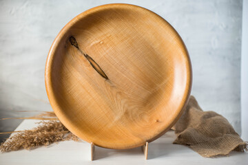 Handmade wooden plate on a stand. Craft textured tableware. Wood texture