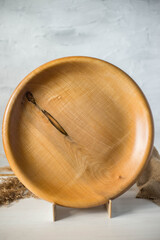 Fototapeta premium Handmade wooden plate on a stand. Craft textured tableware. Wood texture