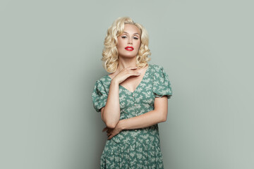 Cute woman with makeup and blonde curly hair wearing green dress on light green banner background