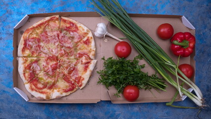 Tasty pizza and fresh cooking ingredients on a table