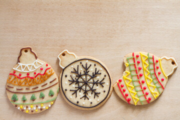 Hand decorated cookies in shape of baubles on kitchen board, christmas background 