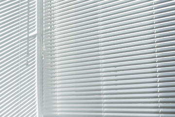 aluminum venetian white closed blinds hanging on window in office room
