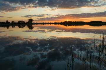 Beautiful sunset over a calm lake and reflection of clouds in the water