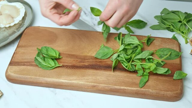 A close-up look of chopping and sorting basil leaves on a cutting board in 4K.