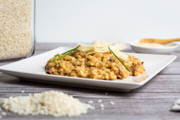 Risotto con parmesano en un plato blanco encima de un fondo gris rústico